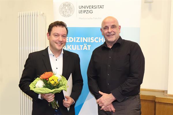Dr. Armin Frille lächelnd im Jackett und mit Blumenstrauß in der Hand, rechts daneben Dekan Bechmann, ebenfalls lächelnd