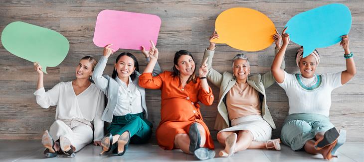 Frauen sitzend, halten Sprechblasen hoch