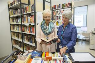 Frau schlägt Buch in der Patientenbibliothek auf