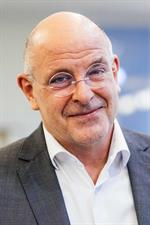 Portrait of an elderly man with bald head, round rimless glasses, white shirt and gray jacket