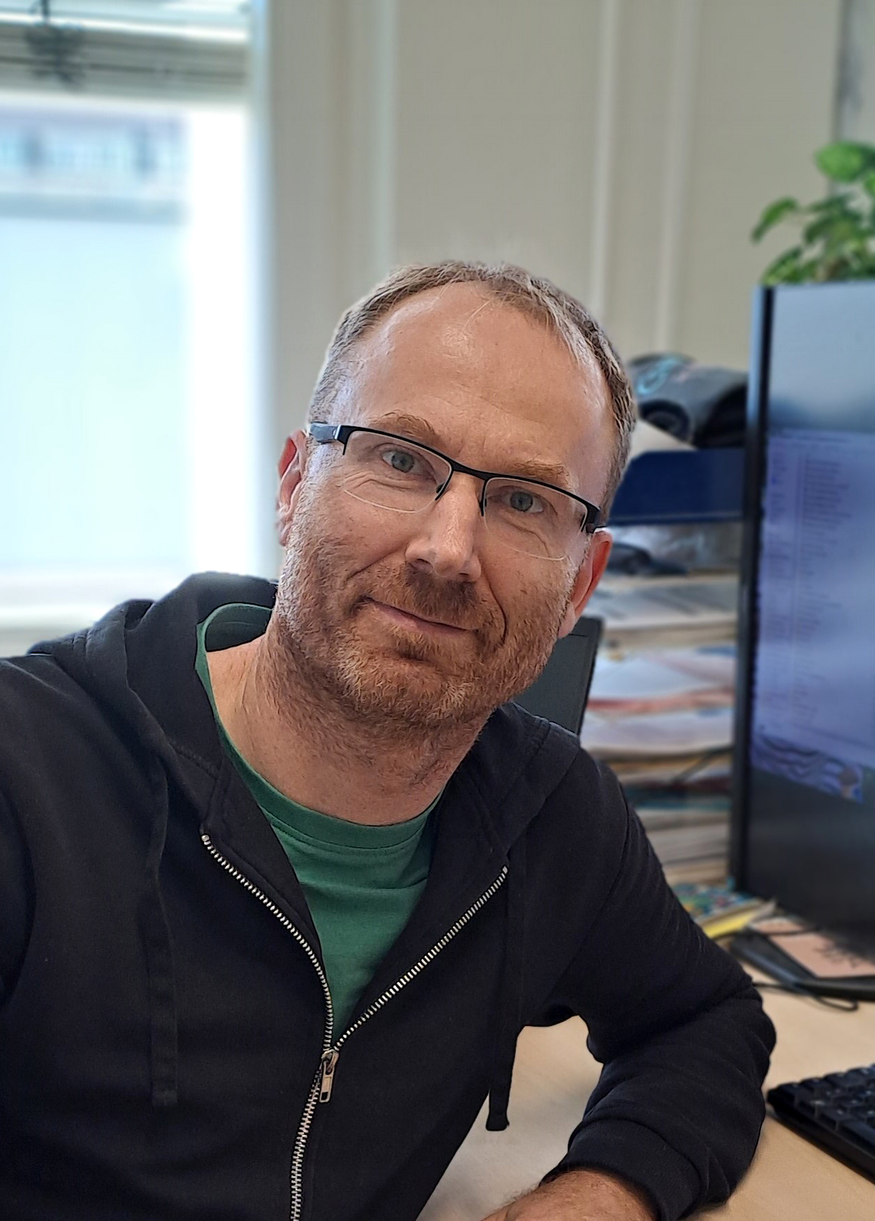 Lächelnder Mann mit kurzen rotbraunen Haaren und Brille