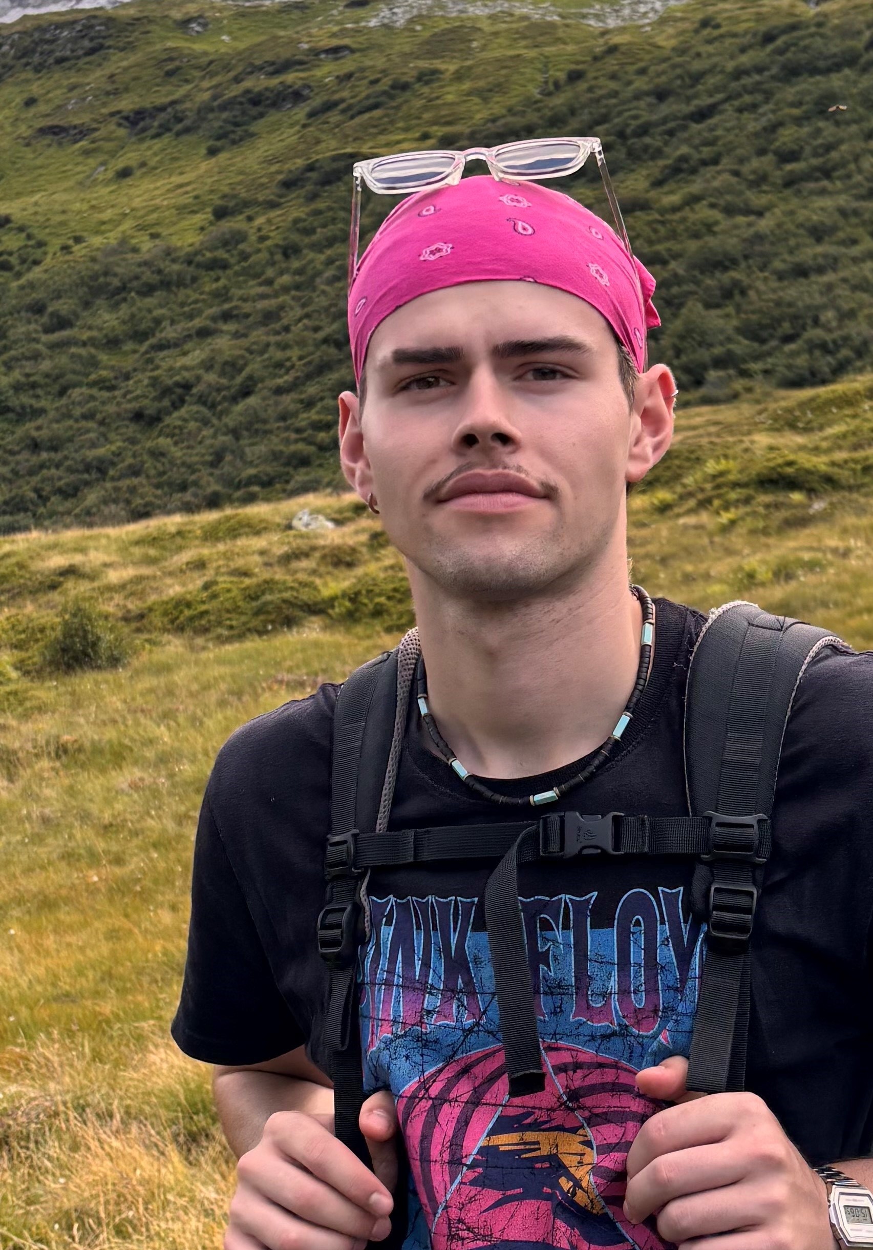 Ein mann in einer blauen jacke mit kapuze steht vor einem fluss