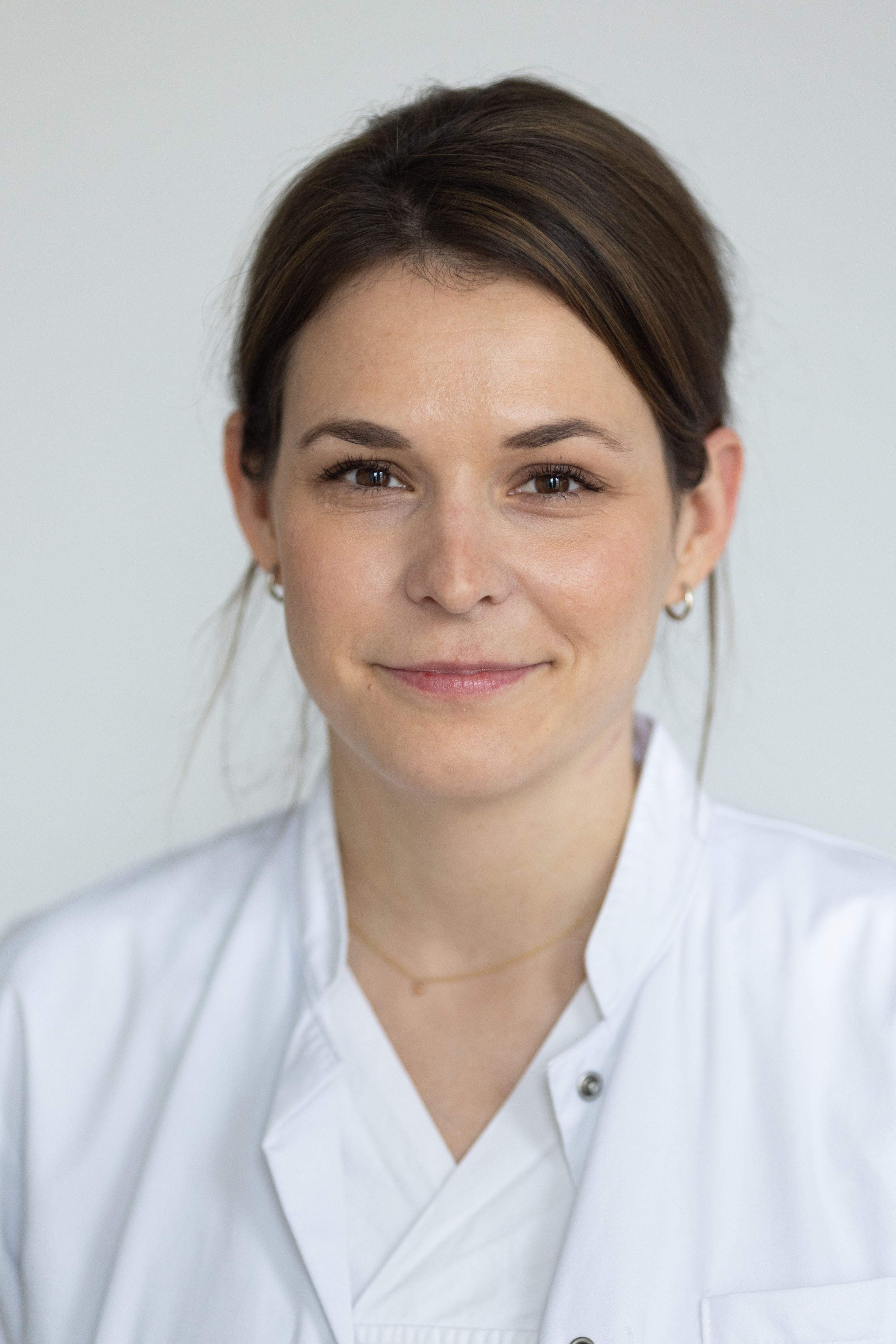 Eine frau im weißen laborkittel lächelt in die kamera