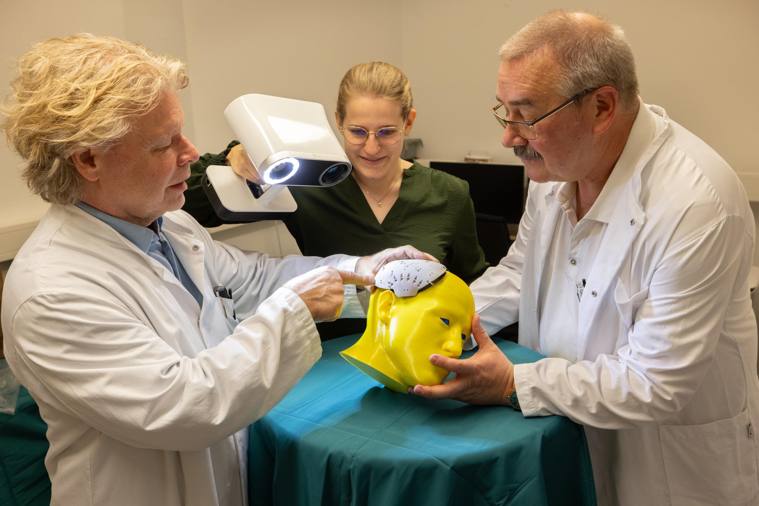 Prof. Dirk Winkler, Direktor der Klinik und Poliklinik für Neurochirurgie, Katharina Scheidt, wissenschaftliche Mitarbeiterin, und Oberarzt Dr. Christian König (v. l.) betrachten das zu untersuchende Schädelimplantat.