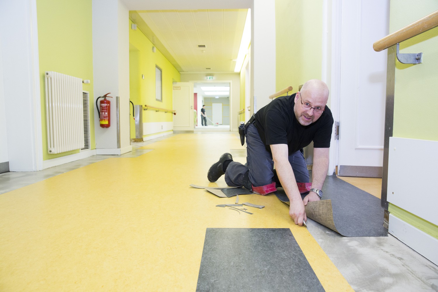 Mike Wanzke, Fachmann der Firma Wohnfühl Konzepte GmbH, verlegt den neuen Fußboden in den Gängen des UKL-Zentrums für Psychische Gesundheit.