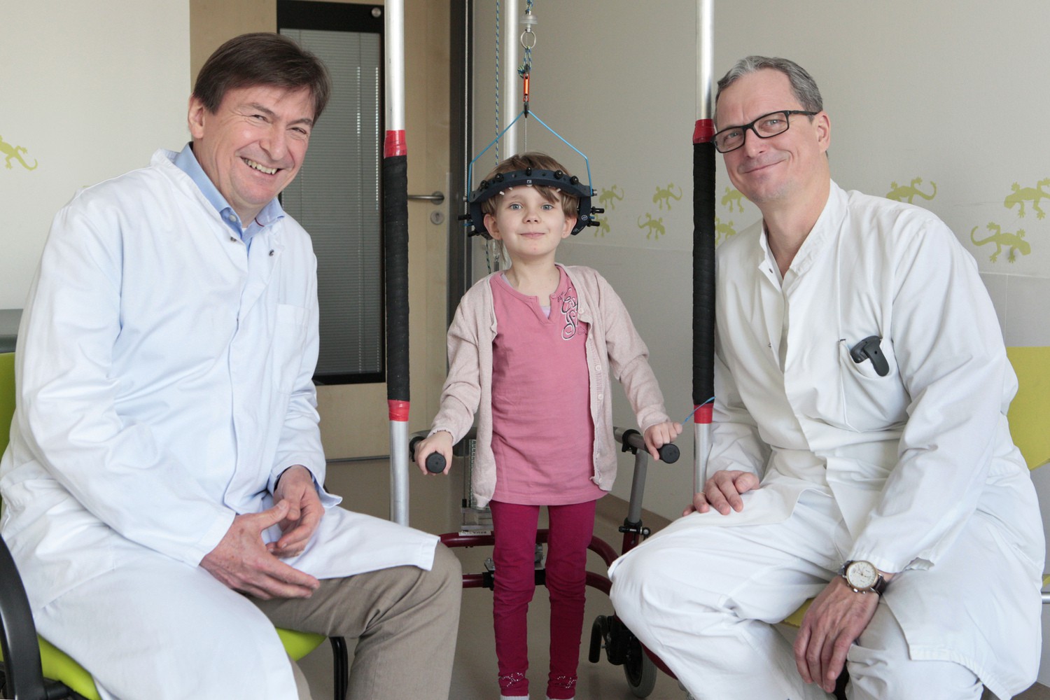 Prof. Christoph Heyde (re.), Leiter des neuen Kinderwirbelsäulenzentrums, und sein Stellvertreter, Prof. Jürgen  Meixensberger (li.) mit der fünfjährigen Savannah. Ihre Wirbelsäule soll mit Gewichten, die an ihrem Kopf befestigt sind, in die richtige Form gebracht werden.