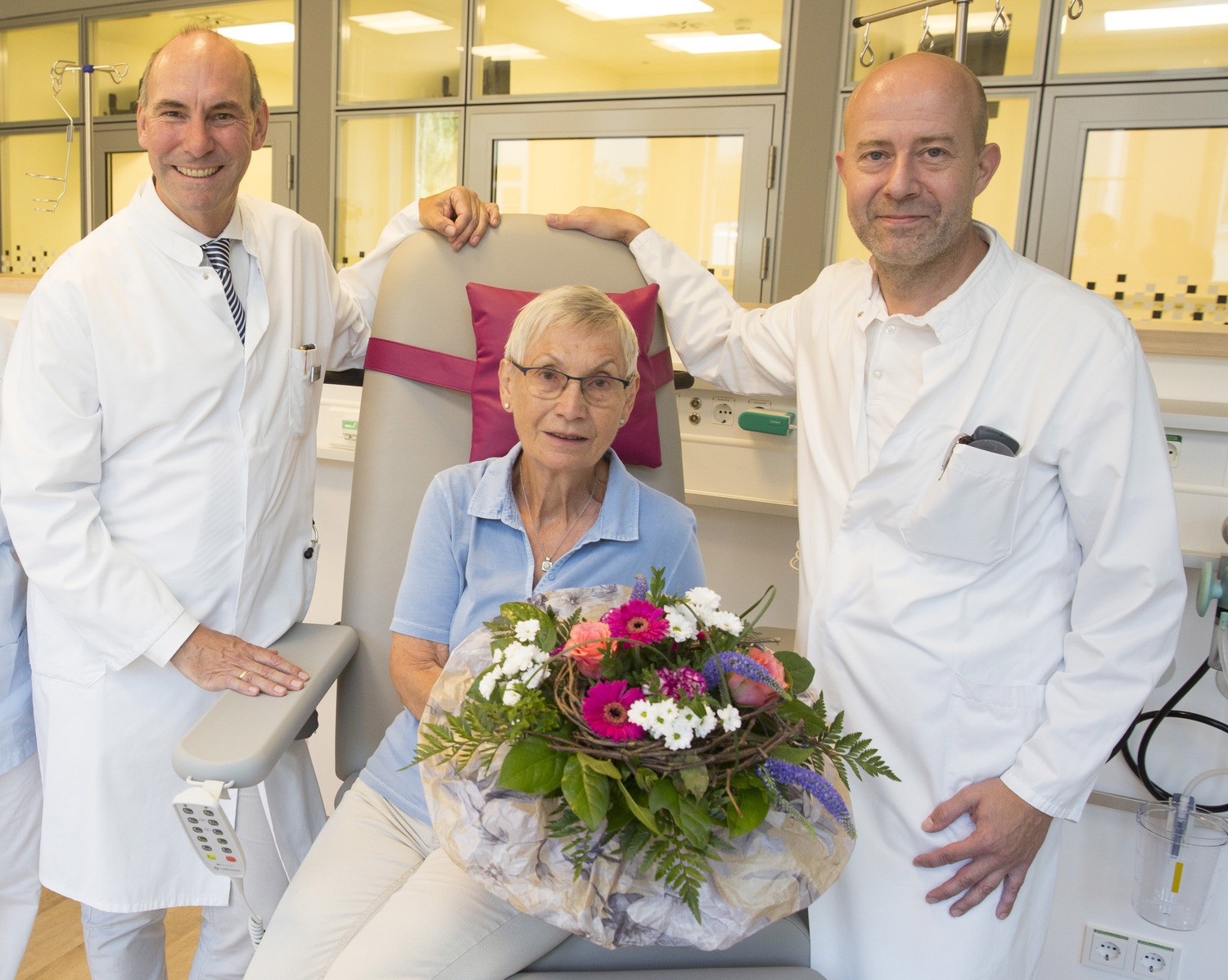 Prof. Florian Lordick (li.), Direktor des Universitären Krebszentrums Leipzig (UCCL), und Dr. Dirk Forstmeyer (re.), Oberarzt und Leiter der Tagesklinik, begrüßen Elke Pauli aus Leipzig als erste Patientin in den Räumen der UCCL-Ambulanz im Klinikneubau Haus 7 des UKL.