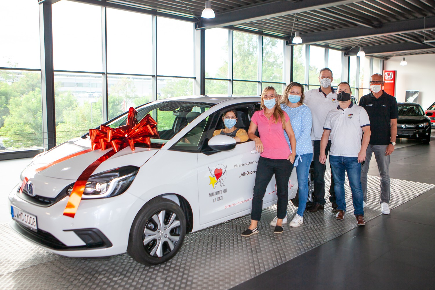 Mobil zu sein ist für ihre Arbeit enorm wichtig: Katrin Mühler (3.v.l.), Leiterin des Nachsorgeteams, Koordinatorin Christin Henri-Dreßler (2.v.l.) und Julia Rothmann (li., im Auto) vom Nachsorgeteam freuen sich über das neue Fahrzeug aus den Händen von Sven Graser (3.v.r.), Vorsitzender des Vereins „Paulis Momente hilft“, seinem Stellvertreter Ingo Schulz (2.v.r.) sowie Robert Wagner (re.), Verkaufsleiter Honda Center Leipzig.