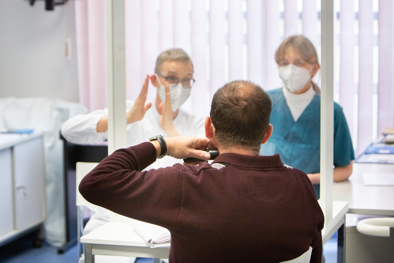 Prof. Michael Fuchs (hinten links), Leiter der Sektion Phoniatrie und Audiologie an der HNO-Klinik des UKL, und Ulrike Sievert, Ulrike Sievert (Foto), Fachtherapeutin für Laryngektomierte, im Beratungsgespräch mit einem Patienten nach einer Kehlkopf-Totaloperation.