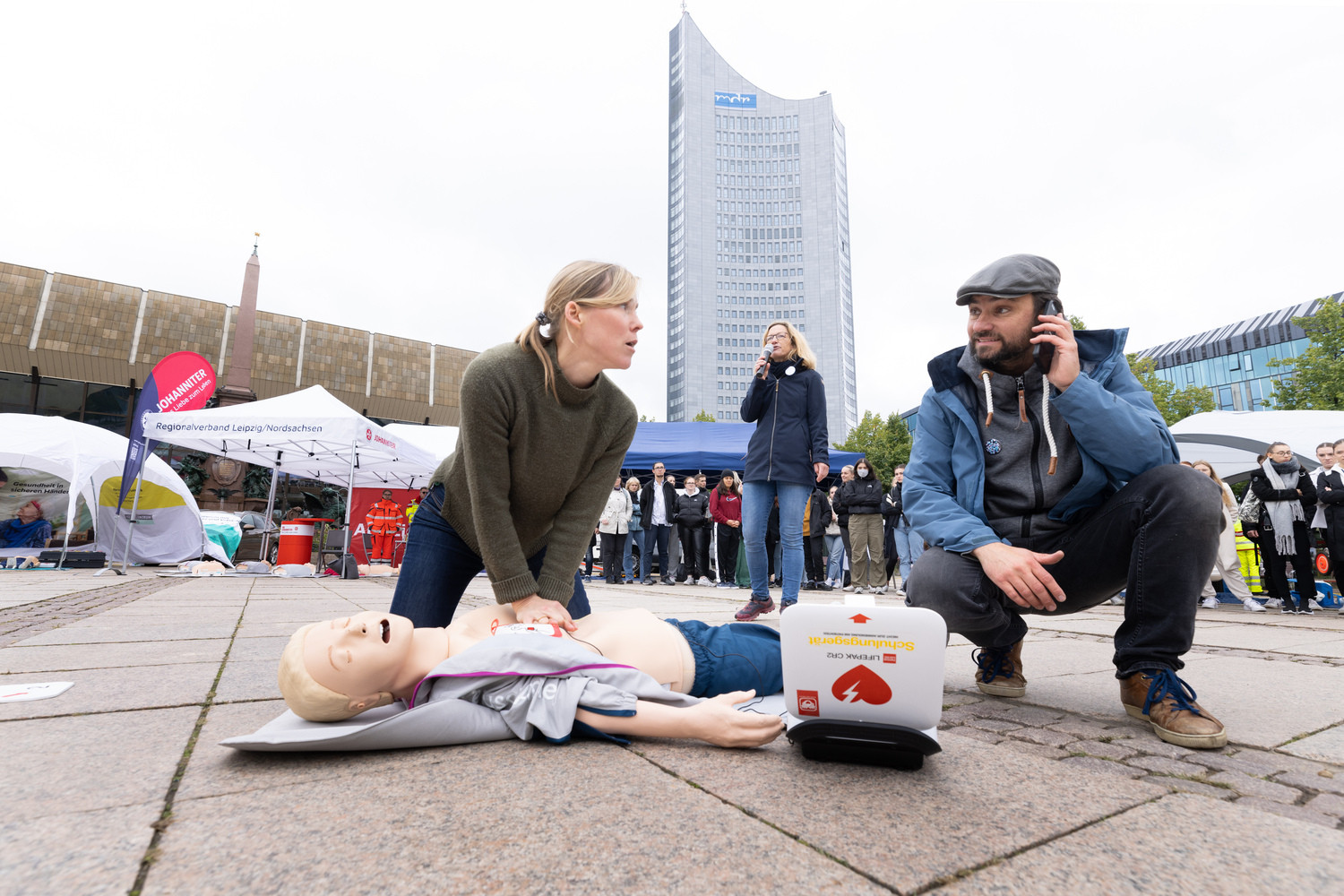 Wie hier kürzlich beim Aktionstag „Leipzig drückt“ auf dem Augustusplatz führen am 27. September und 8. November medizinisch geschulte Schauspieler:innen durch die Herzretter-Kurse. Im Hintergrund mit Mikro: Dr. Alexandra Ramshorn-Zimmer.