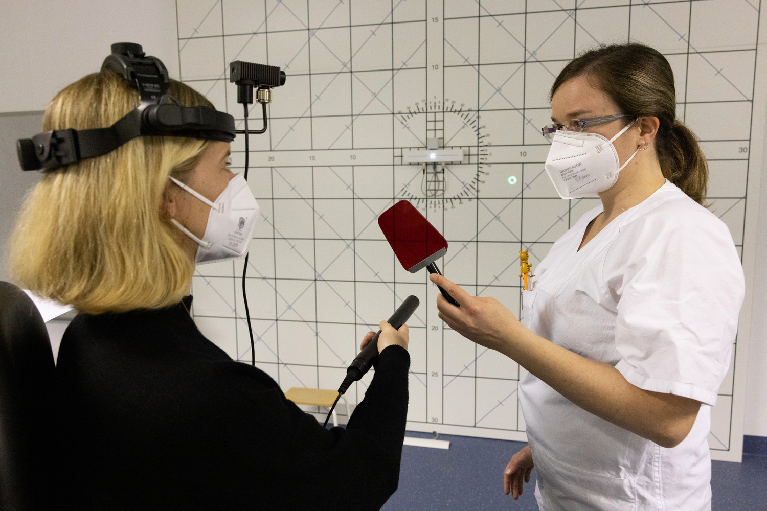 Katrin Obst (re.), Fachbereichsleiterin Orthoptik an der MBFS, nimmt bei einer Patientin eine Diplopieprüfung, auch Doppelbildprüfung genannt, an der Tangententafel nach Harms vor.