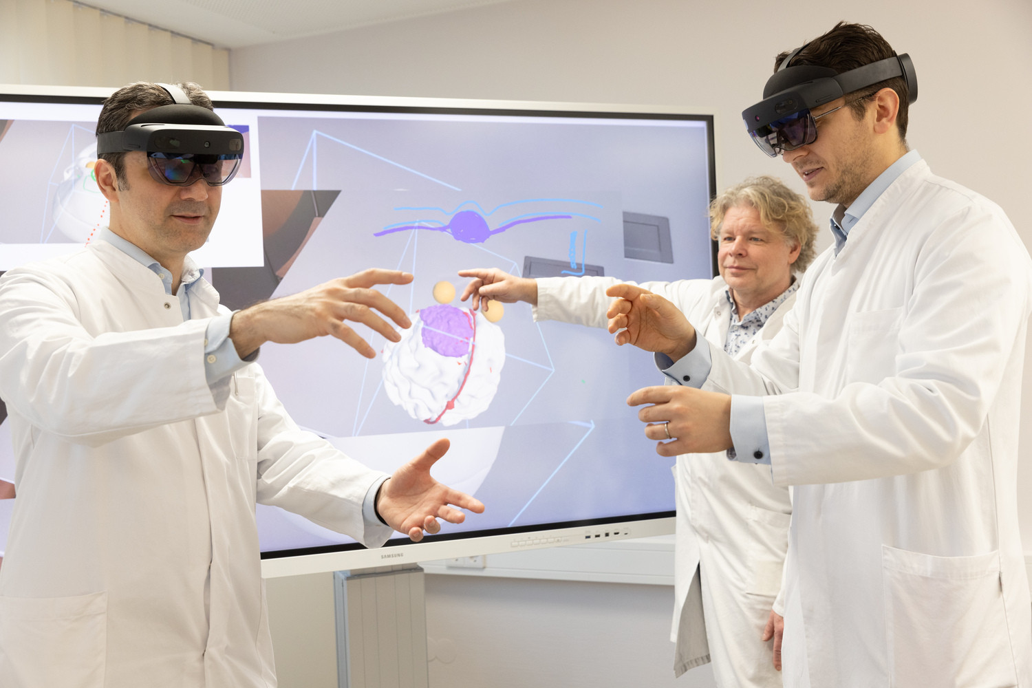 Dank der 3D-Datenbrille, die derzeit von der Arbeitsgruppe um Prof. Dirk Winkler (Mitte, hinten) entwickelt wird, können die Neurochirurgen Prof. Erdem Güresir (li.) und Dr. Johannes Wach die sogenannte „erweiterte Realität“ bei ihrer Arbeit nutzen. Das UKL-Expert:innen-Team entwickelt derzeit zusammen mit Partnern ein virtuelles Navigationssystem für noch sicherere Eingriffe im Kopf.